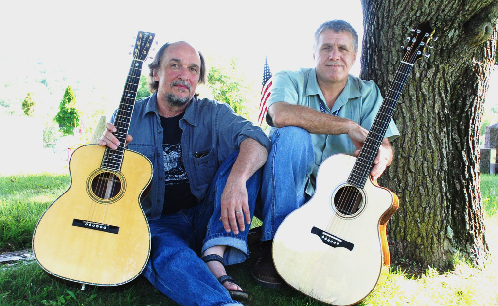 two men with guitars under a tree